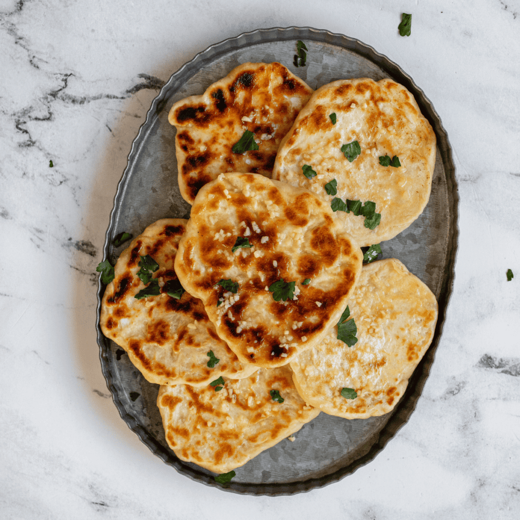 Freshly cooked Blackstone Naan on the griddle, golden brown and soft, ready to serve