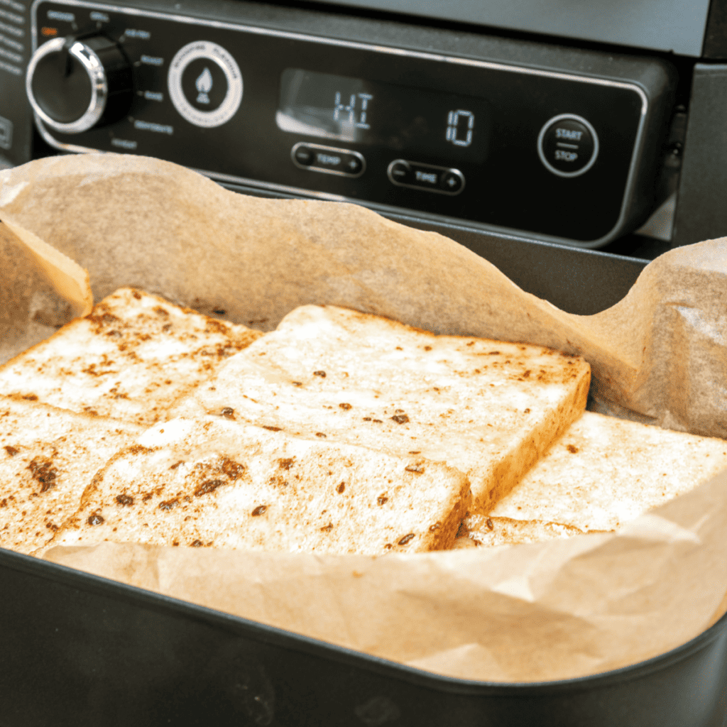 Soaked French toast slices arranged in a greased casserole dish, ready to bake.