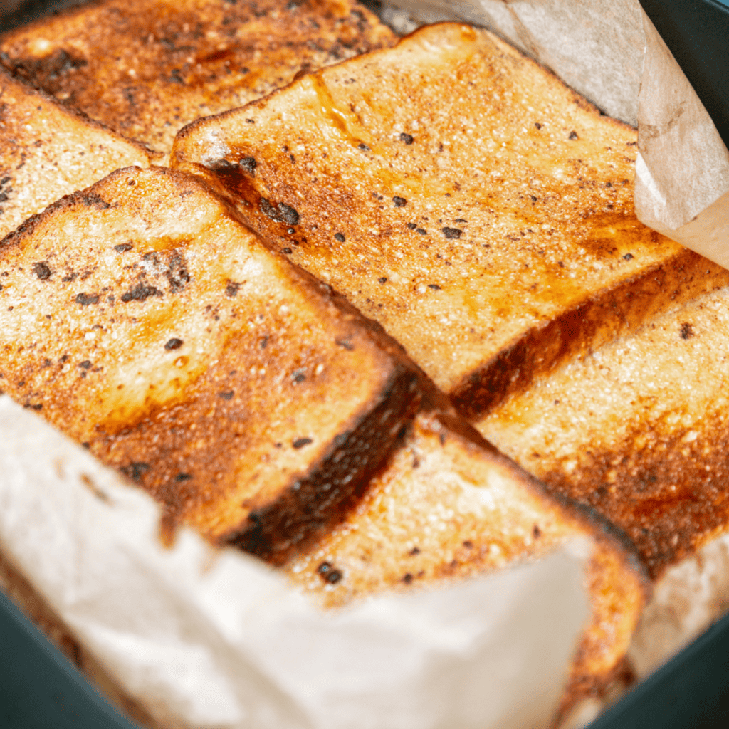 Golden-brown Ninja Woodfire Grill French Toast served with syrup and fresh fruit on a plate.