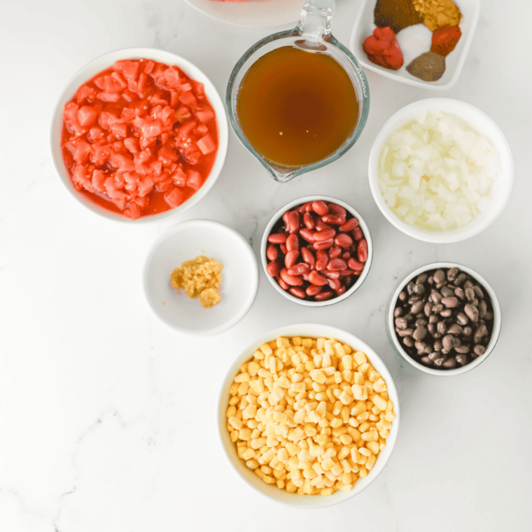 Ingredients for chicken enchilada soup including chicken breasts, enchilada sauce, black beans, corn, and spices