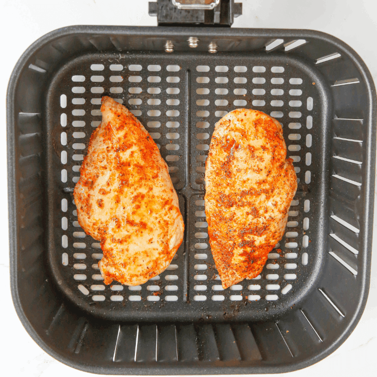 Golden cooked chicken breasts in the air fryer basket at 165 degrees F for shredded buffalo chicken