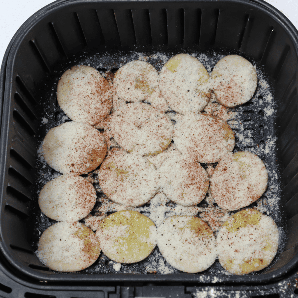 Season the sliced potatoes in the air fryer basket.