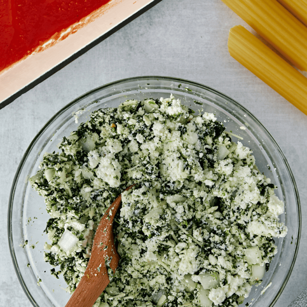 Stuffing cooked manicotti pasta tubes with creamy ricotta and spinach filling