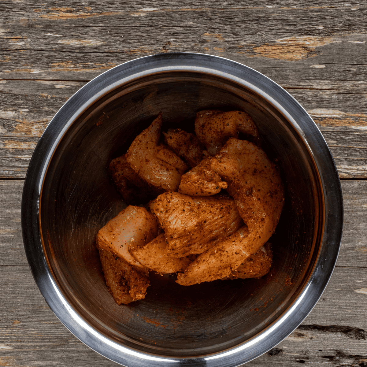 Diced chicken tossed with taco seasoning and lime juice in a glass mixing bowl