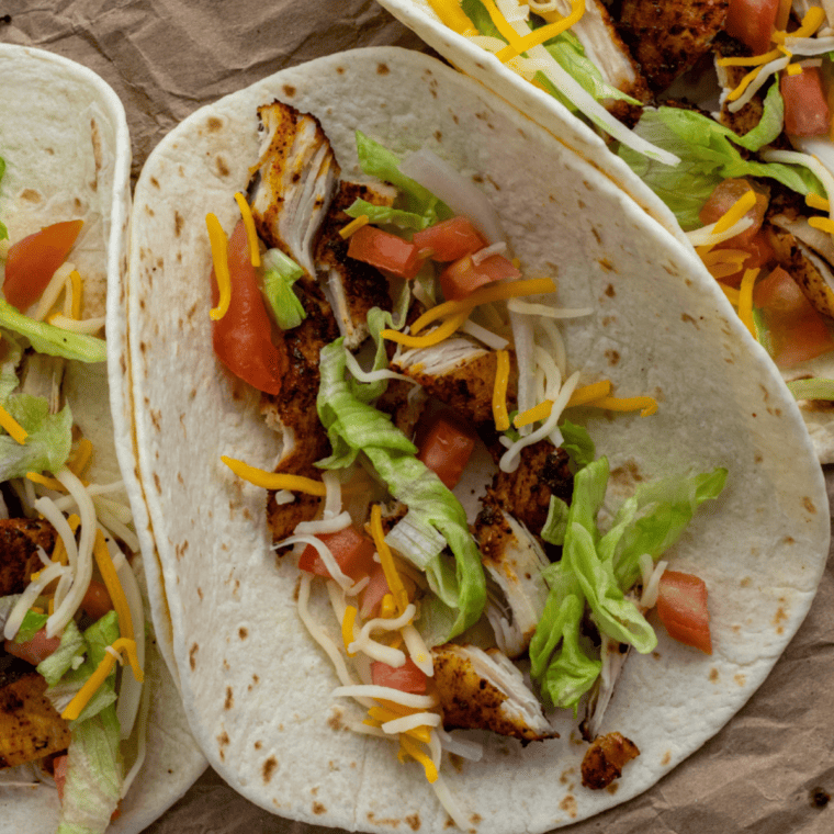 Overhead view of air fryer chicken street tacos served with lime wedges and salsa