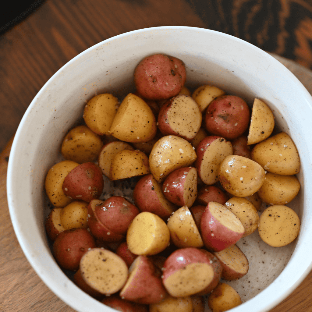 Potatoes sliced and seasoned with olive oil, garlic, and parmesan, ready for air frying.