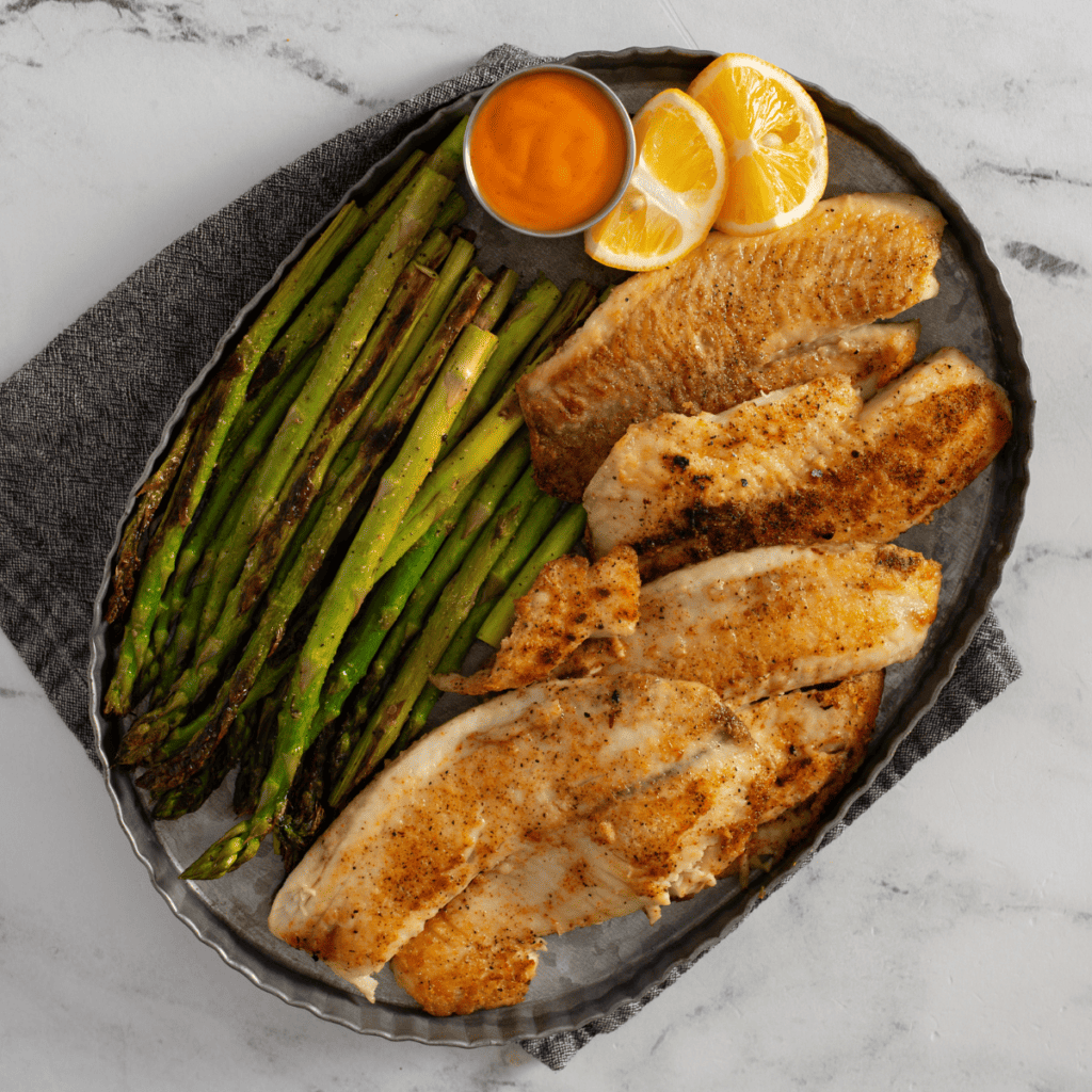 Blackstone catfish fillet on a plate with lemon wedges and parsley