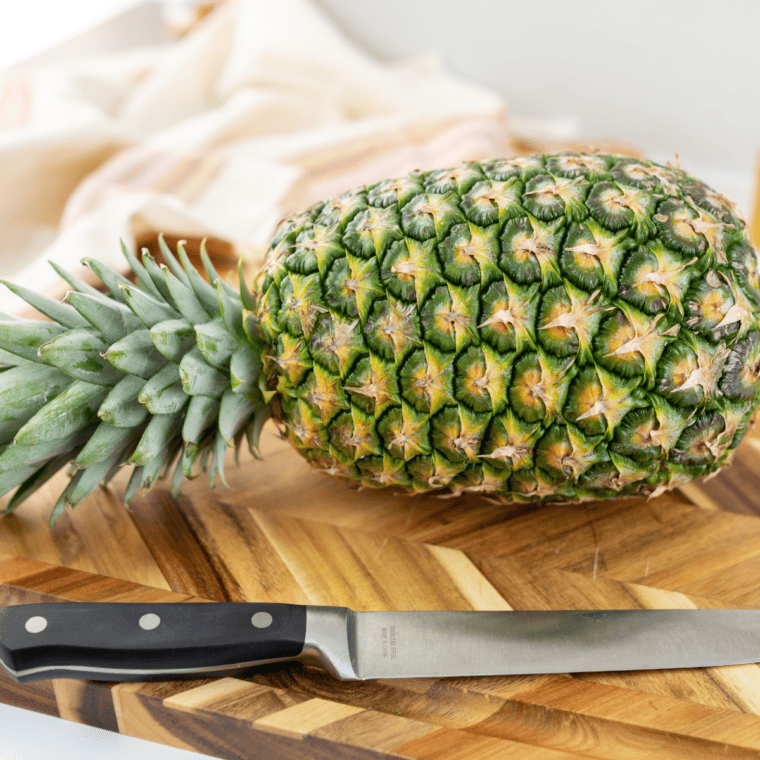 Fresh pineapple being trimmed and peeled, removing skin and brown eyes.