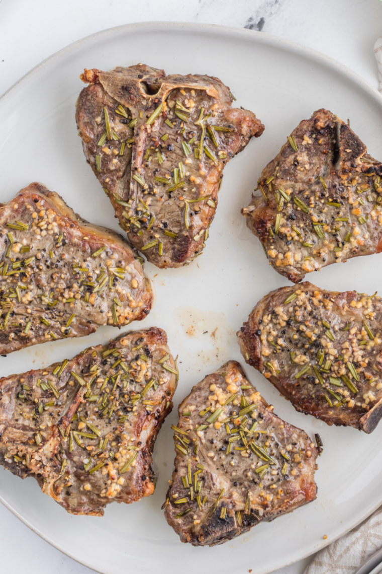 Juicy reheated lamb chops on a white plate