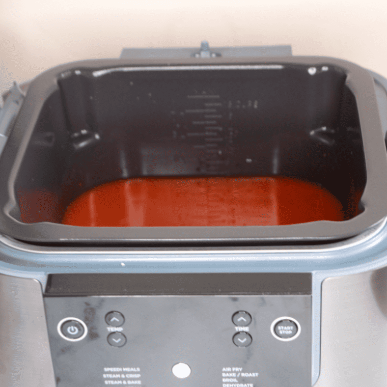 Ninja Speedi pot with uncooked spaghetti layered over tomato sauce, water, and Italian seasoning, fully submerged before cooking.