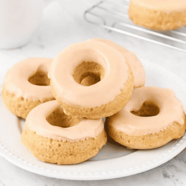 Glazed air fryer protein donuts stacked on a white plate with one showing a bite taken out