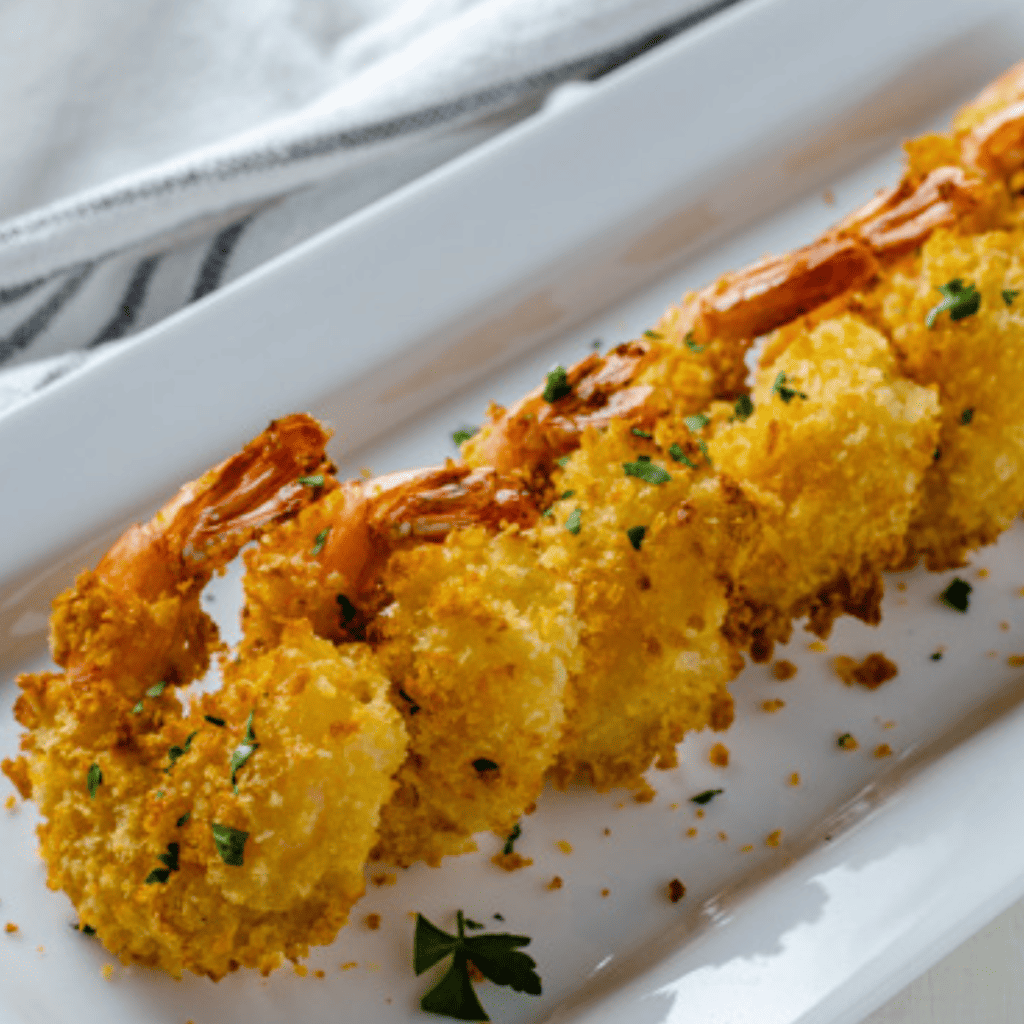 Crispy Bang Bang Shrimp tossed in creamy sweet and spicy sauce served on a plate with lettuce garnish for a restaurant style appetizer at home.