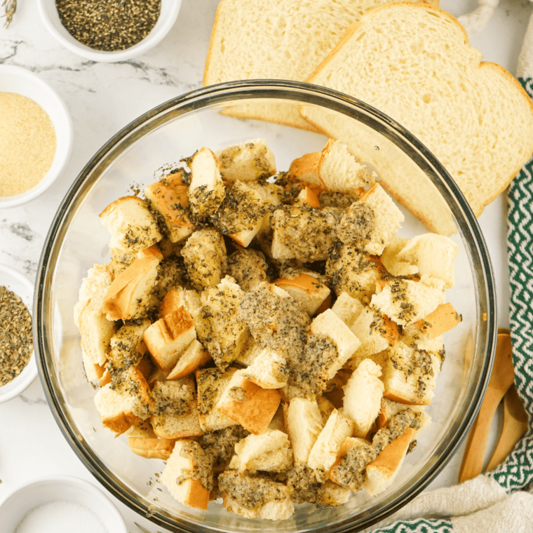 Coating the bread cubes in the herb olive oil mixture.
