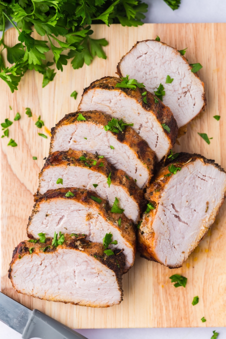 Frozen pork tenderloin seasoned and cooking in an air fryer basket.