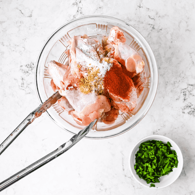 Marinating chicken wings in General Tso sauce in a mixing bowl for Air Fryer preparation.