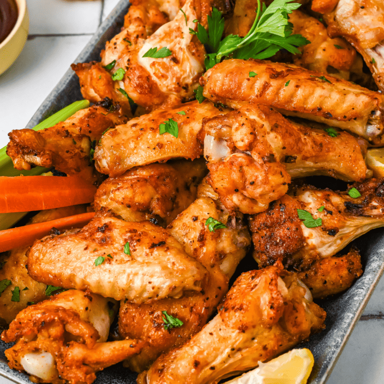 Plate of Air Fryer General Tso Wings, beautifully glazed with sauce and garnished with sesame seeds and green onions, served with a side of dipping sauce.