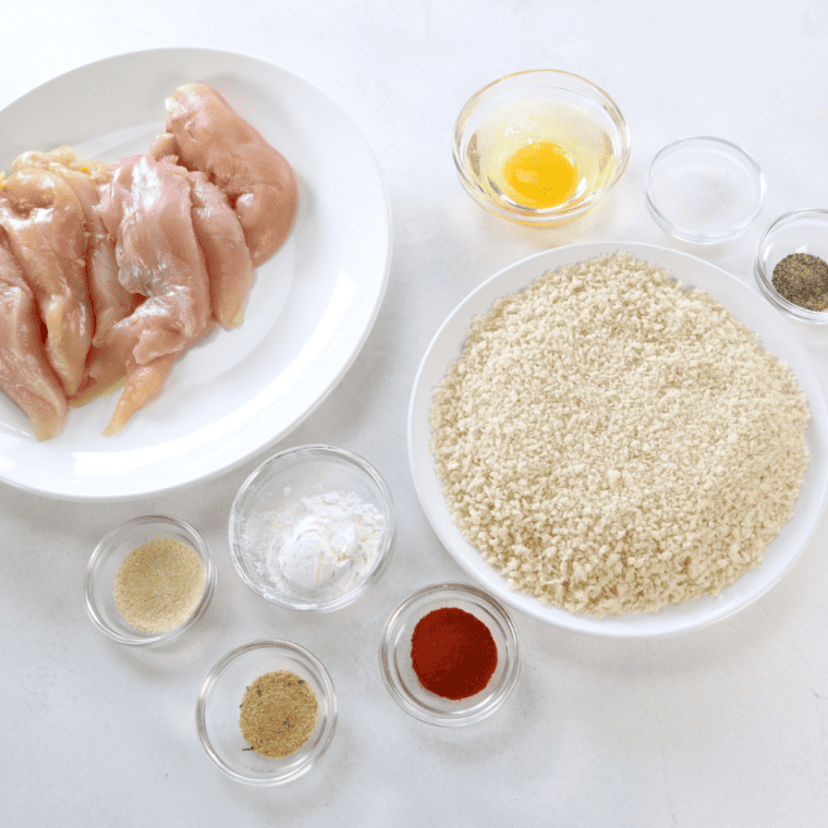 Raw chicken tenders patted dry on a cutting board before breading