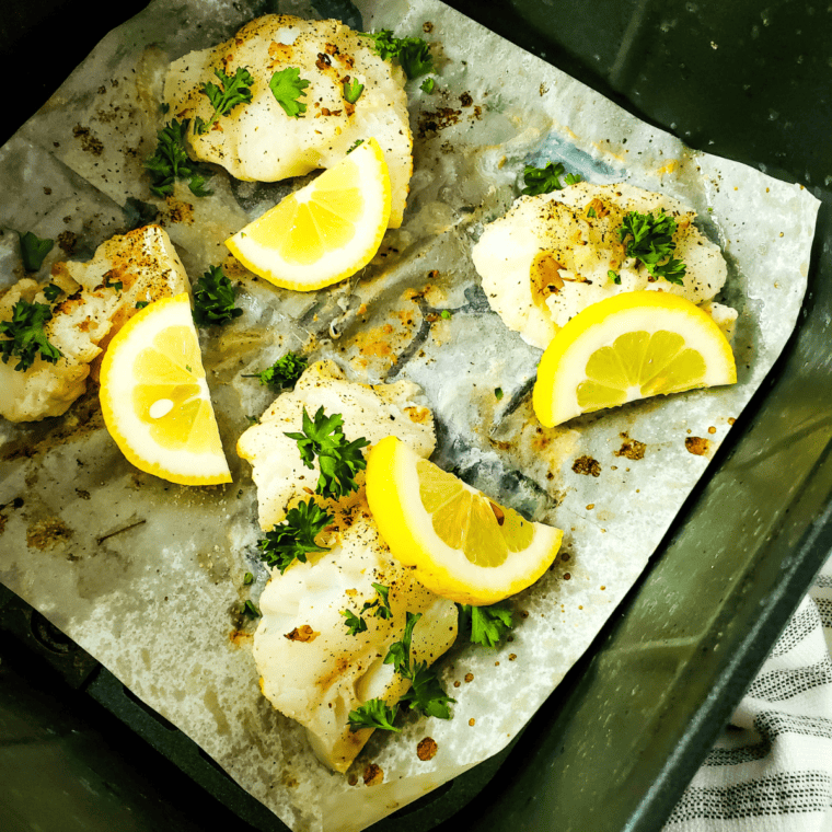 Air Fryer Lemon Pepper Cod fillets with a crispy, golden crust, garnished with lemon slices.