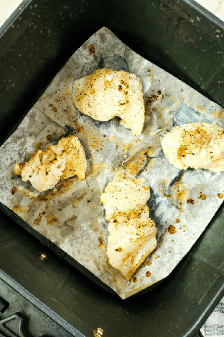 Placing marinated cod fillets in the air fryer basket, ensuring no overlap, and setting the cook time.