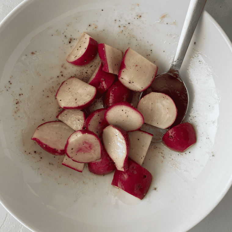 Air fryer basket with seasoned radishes set for cooking at 375°F.