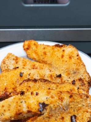 Blackstone tilapia fillets sizzling on a hot griddle with golden brown seasoning crust