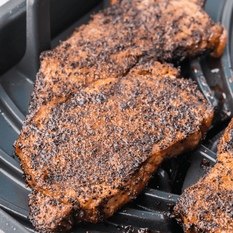 Air fryer basket with steak and no coffee filter lining the bottom