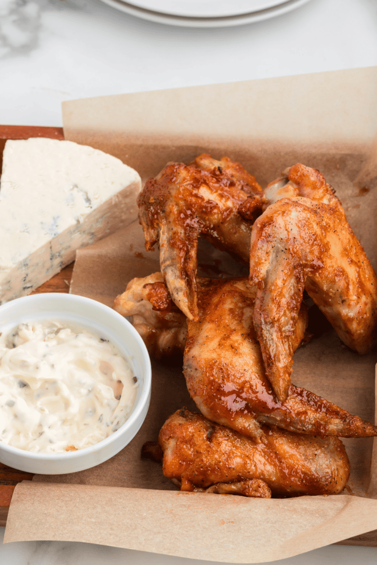 Crispy chicken wings coated in glossy buttery Hooters-style wing sauce on a plate