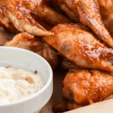 Bowl of homemade copycat Hooters wing sauce with a whisk resting on the side