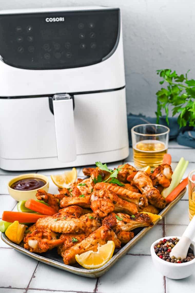 Delicious Air Fryer Copycat Buffalo Wild Wings General Tso Wings, coated in a glossy sweet and spicy sauce, served on a platter with garnishes of sesame seeds and chopped green onions.