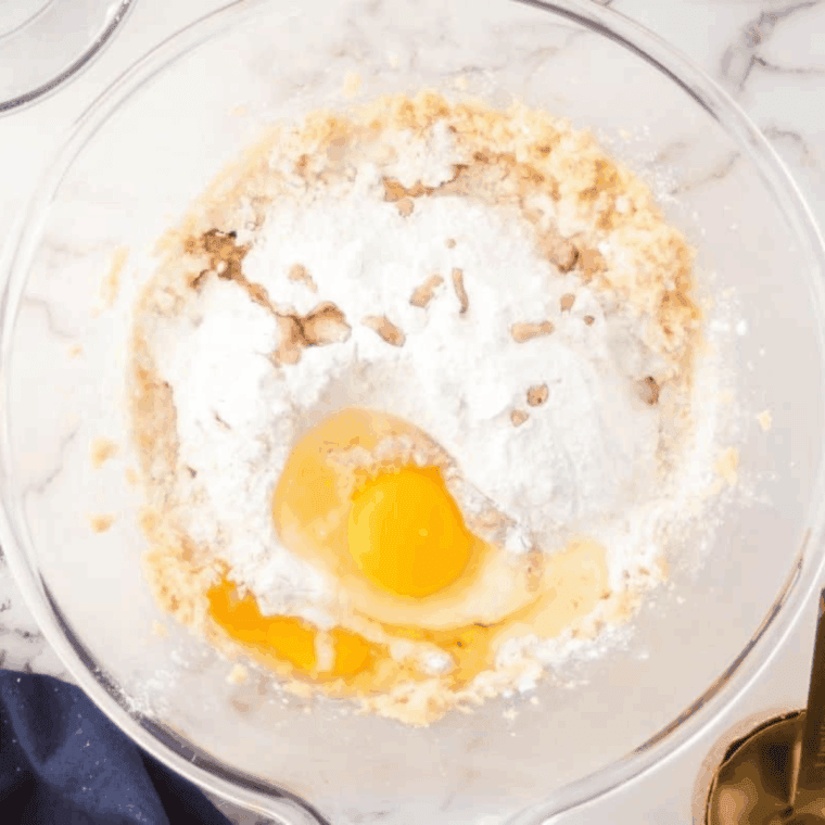 Whisking almond flour, baking powder, and salt in a bowl, then mixing into wet ingredients to form smooth batter.