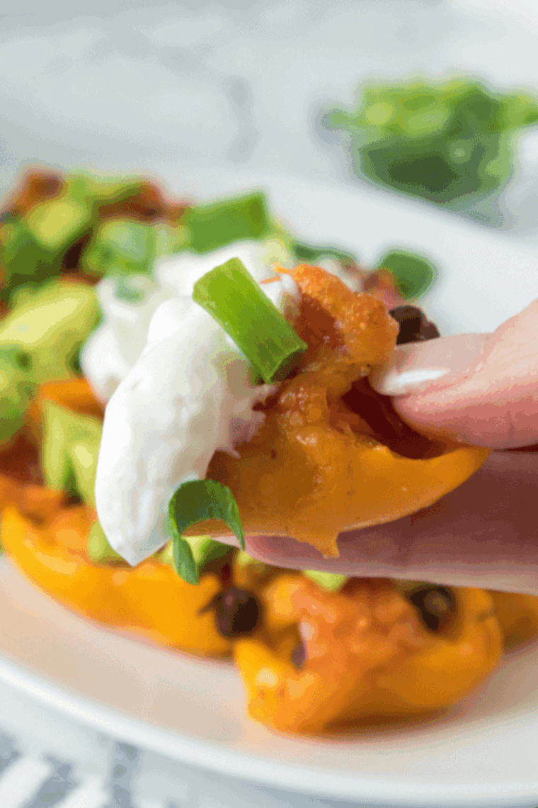 Air fryer stuffed mini peppers filled with melted cheese and topped with diced avocado and scallions