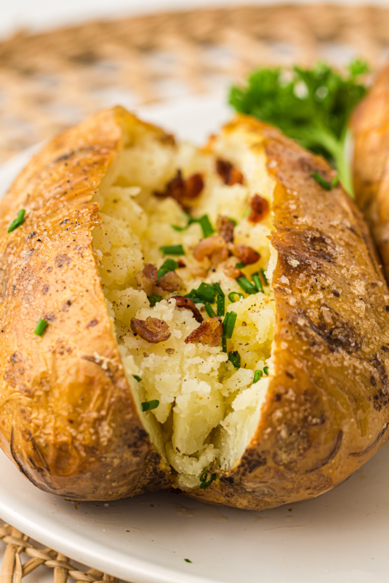 Two Ninja Crispi baked potatoes on a plate with classic butter and sour cream toppings