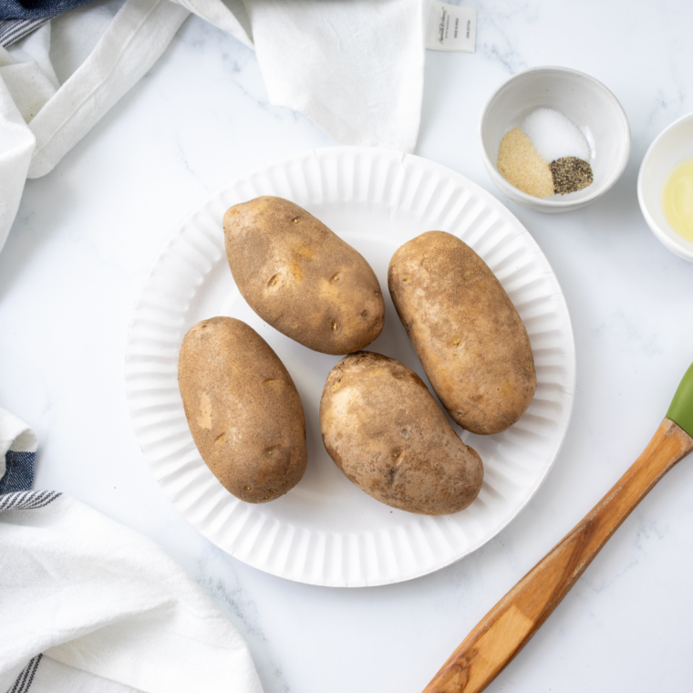 Russet potatoes, olive oil, and coarse sea salt laid out for Ninja Crispi baked potatoes