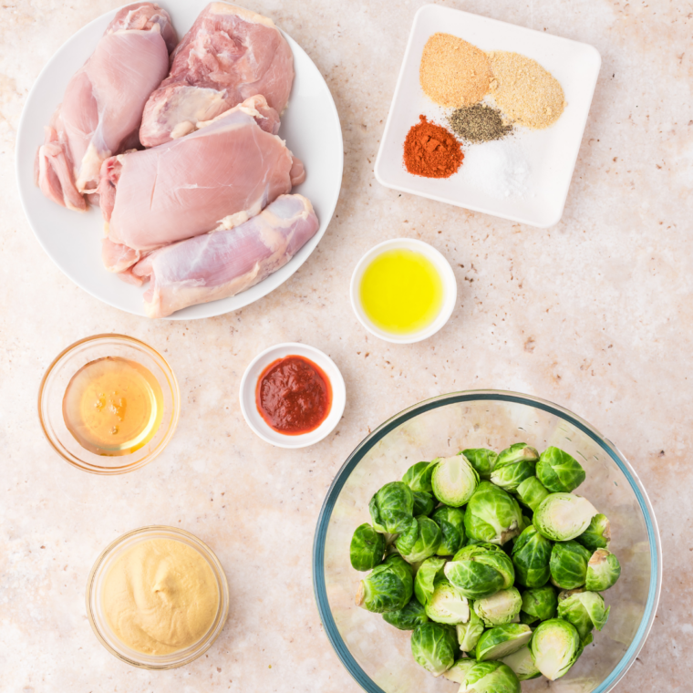Fresh Brussels sprouts, olive oil, salt, pepper, and garlic powder arranged on a table