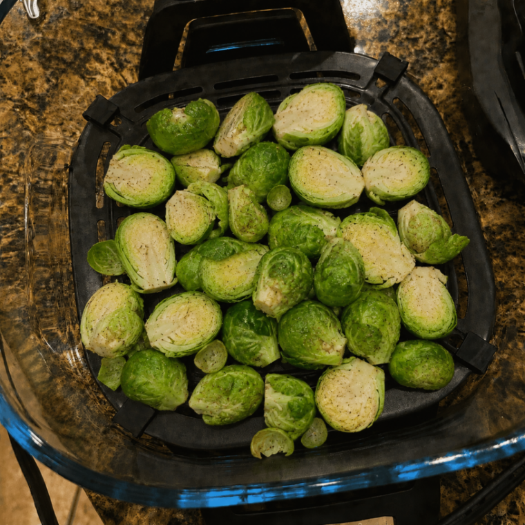 Seasoned Brussels sprouts arranged cut-side down on the Ninja Crispi crisper plate