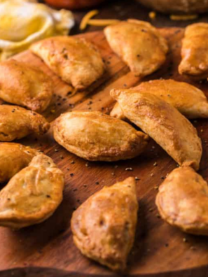 Golden brown air fryer frozen empanadas on a wooden cutting board