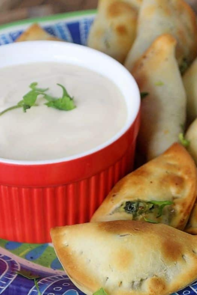 Air fryer empanadas on a plate with a bowl of chimichurri sauce
