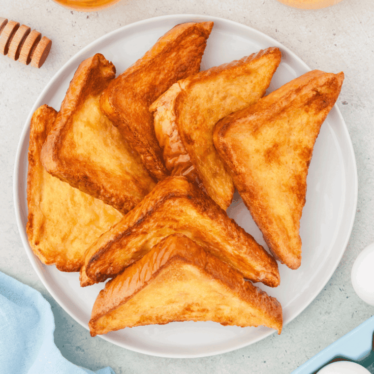 Crispy golden air fryer honey toast topped with melted butter and drizzled honey on a plate.