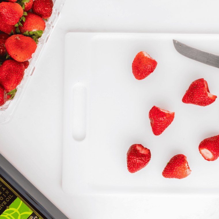 Preheat air fryer to 350°F, while washing, hulling, and quartering strawberries in a large bowl, then tossing them with olive oil.