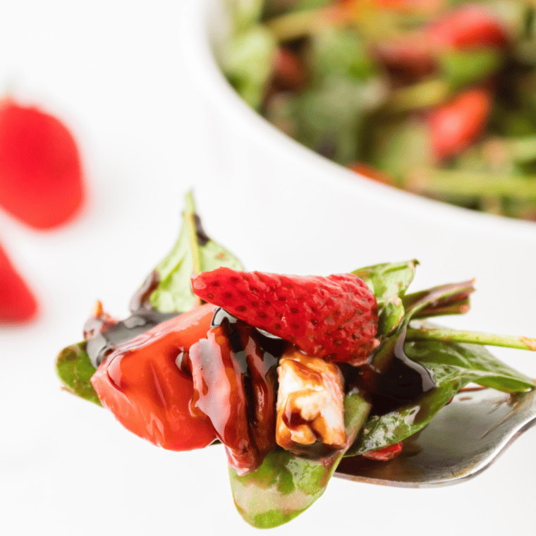 Air Fryer Spinach Strawberry Salad with roasted strawberries, baby spinach, candied pecans, chevre cheese, and balsamic glaze.