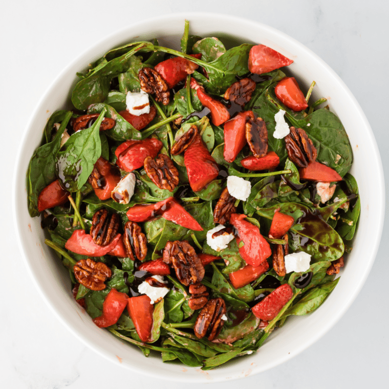 Air Fryer Spinach Strawberry Salad with roasted strawberries, baby spinach, candied pecans, chevre cheese, and balsamic glaze.