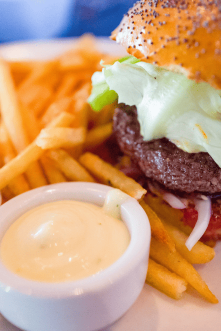 Air fryer lamb burger on a bun with melted cheese, lettuce, and tomato, ready to serve.