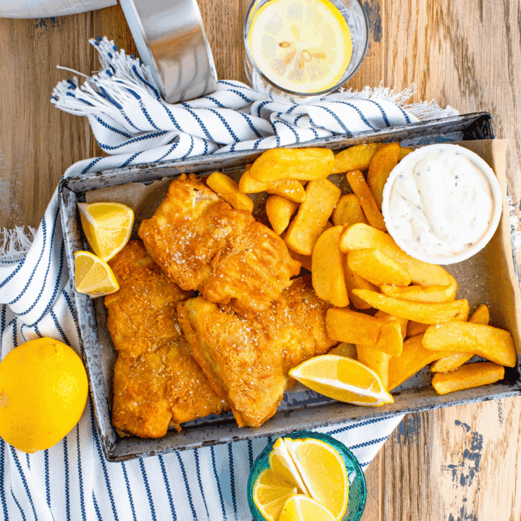 Crispy reheated fish and chips in air fryer basket.r