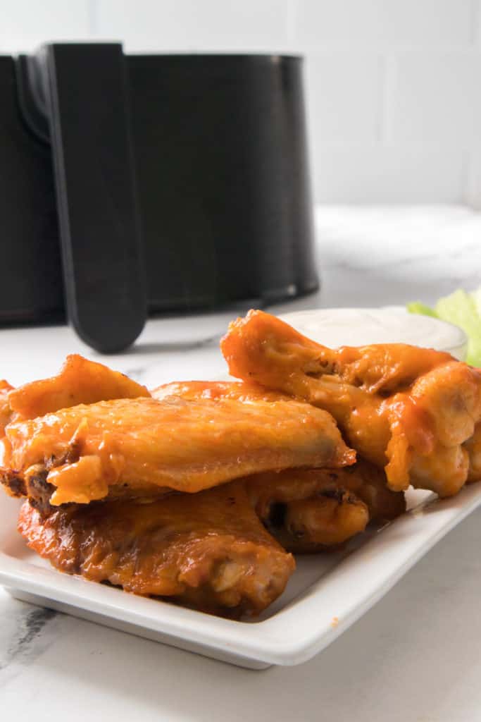 buffalo wings on platter with ranch and celery, air fryer in background