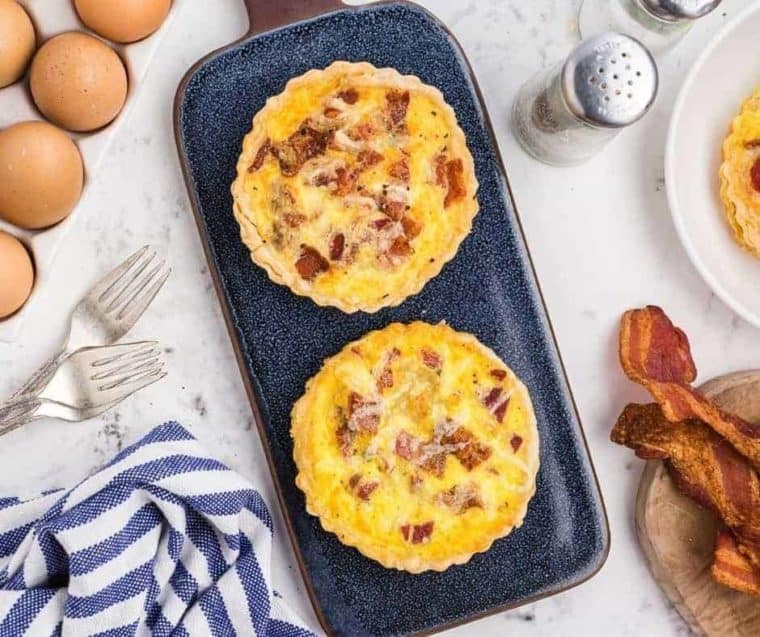two personal sized quiches on a blue serving board