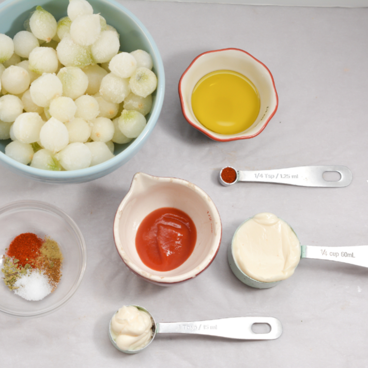 Ingredients for air fryer blooming onion bites: frozen pearl onions, olive oil, paprika, oregano, thyme, cumin, salt, and pepper