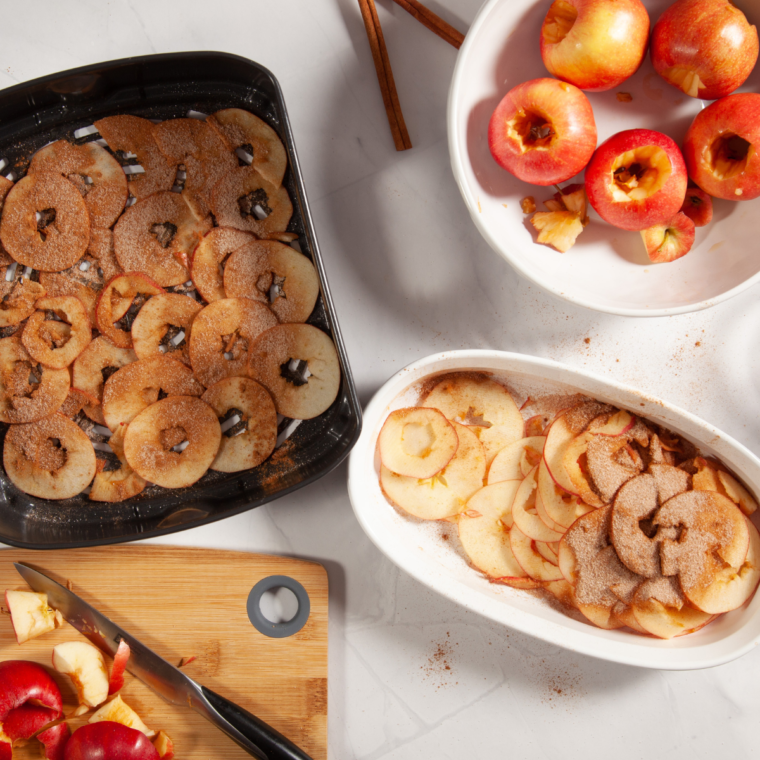 Tossing sliced apples with ground cinnamon in a glass bowl