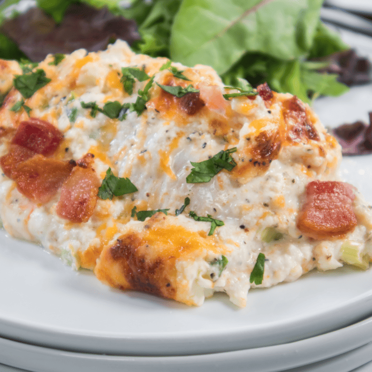 Air fryer jalapeño popper chicken casserole with melted cheese, bacon crumbles, and jalapeño slices in a white baking dish


