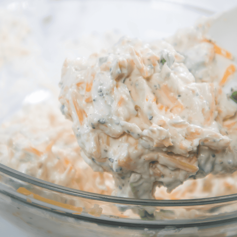 Mixing softened cream cheese, cheddar cheese, jalapeño, green onion, sour cream, and seasonings together in a large bowl for casserole filling