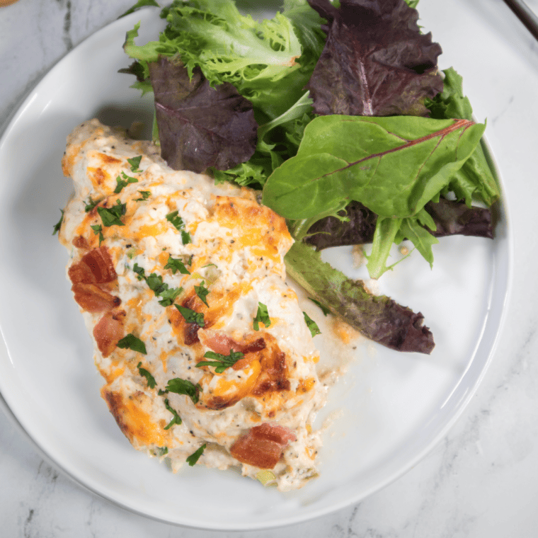 Air fryer jalapeño popper chicken casserole with melted cheese, bacon, and jalapeño slices served in a white baking dish.